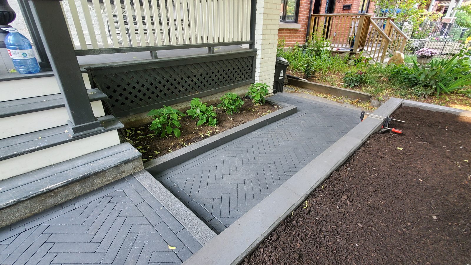Herringbone interlock paving beside the porch and raised garden wall